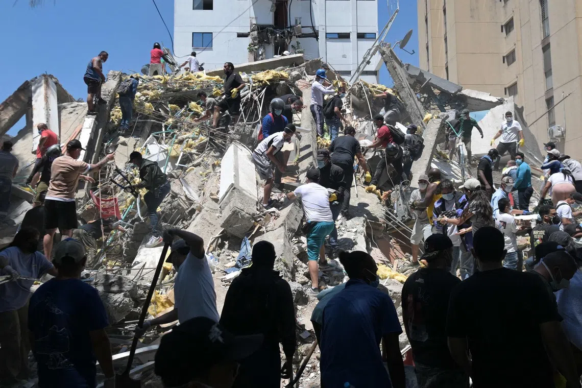 TOPSHOT - People look for survivors amid the rubble of a collapsed building after an earthquake in Cali, Colombia, on August 10, 2026. A powerful earthquake rocked Colombia and neighboring Latin American countries on August 10, 2026, with medical teams rushing to help victims after buildings were damaged or collapsed in several cities. The Colombian geological service and its American counterpart USGS put the magnitude at 7.4, with an epicenter 100 km (60 miles) underground in the west of the country. Colombia had initially put it at 6.6. (Photo by Joaquín SARMIENTO / AFP)