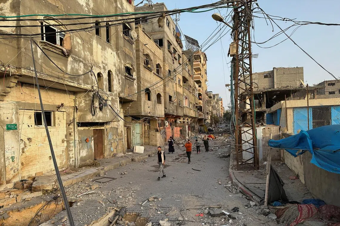 People walking among houses destroyed in Israeli strikes during the conflict, amid a temporary truce between Israel and Hamas, on Nov 26. 