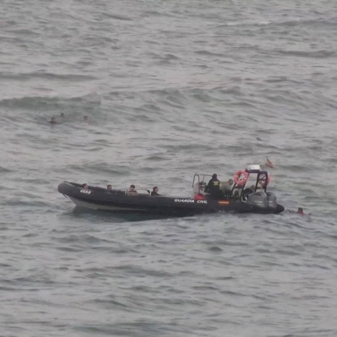A file photo from July 25, 2025 showing migrants reaching a police boat, as at least 54 children and about 30 adults swam from Morocco to Spain’s North African enclave of Ceuta.