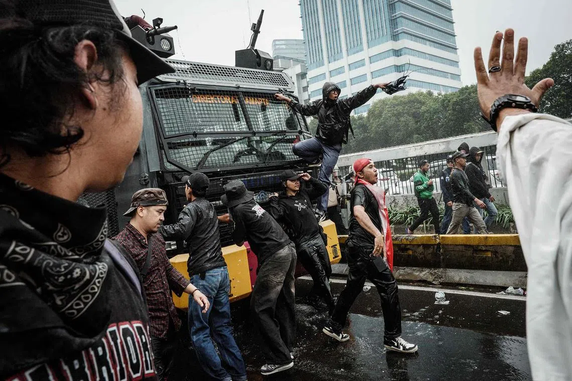 Protesters trying to block a police vehicle with a water cannon mounted during a demonstration demanding the dissolution of parliament in front of the House of Representatives parliament building in Jakarta on Aug 25, 2025. 