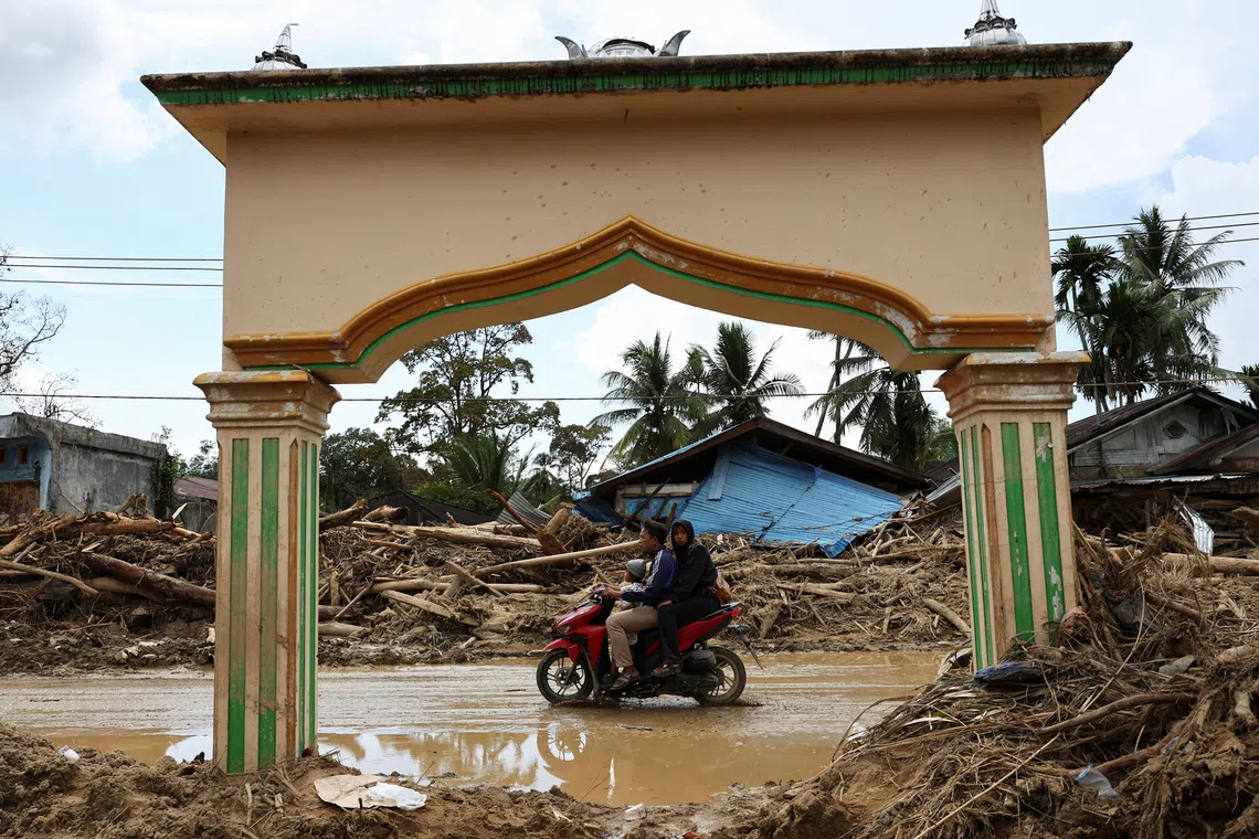 Local residents ride a motorbike at an area following deadly flash flood in Batang Toru, South Tapanuli, North Sumatra province, Indonesia, December 6, 2025. REUTERS/Willy Kurniawan