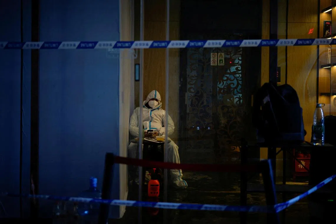 A worker in a protective suit guards an elevator, as coronavirus disease (COVID-19) outbreaks continue in Shanghai, China, December 14, 2022. 