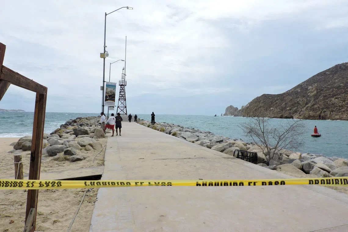 Police officers and lifesavers stand at a breakwater that was closed as a security measure by local authorities while the Category 4 Hurricane Hilary rushes towards Mexico's Baja California peninsula.