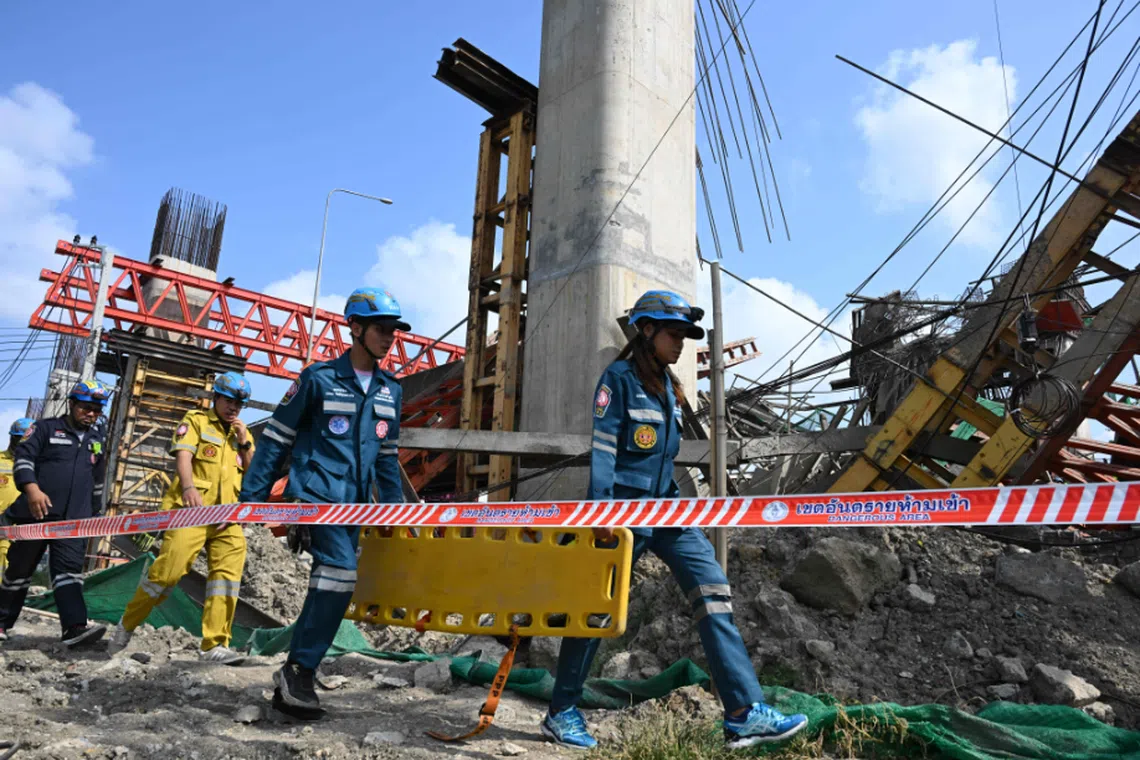 Rescue workers carry a stretcher at the site of a crane collapse along Rama II highway in Bangkok on March 15.
