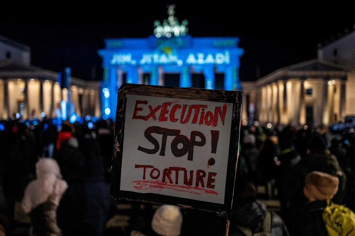 An activist displays a placard inscribed with the words "Stop execution and torture" during a rally in support of demonstrators in Iran, in front of the Brandenburg Gate in Berlin on Dec 13, 2022. 