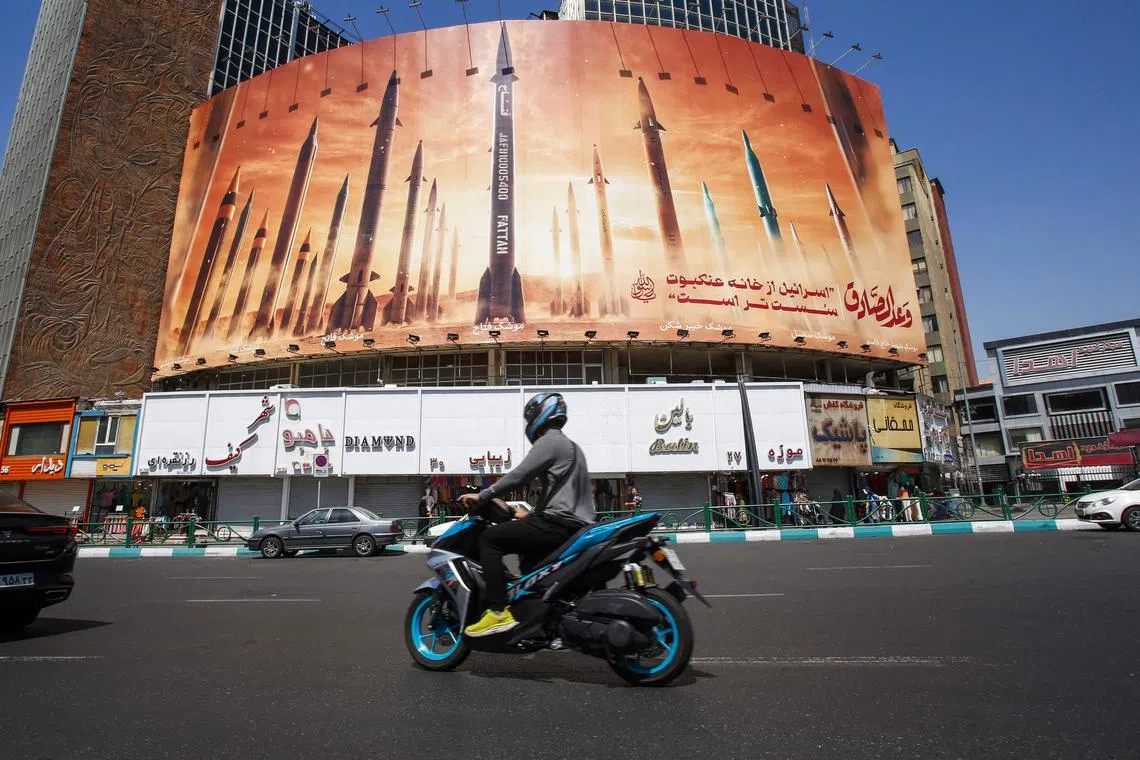 A man riding a motorcycle past a billboard depicting Iranian ballistic missiles in service in Tehran on April 19.