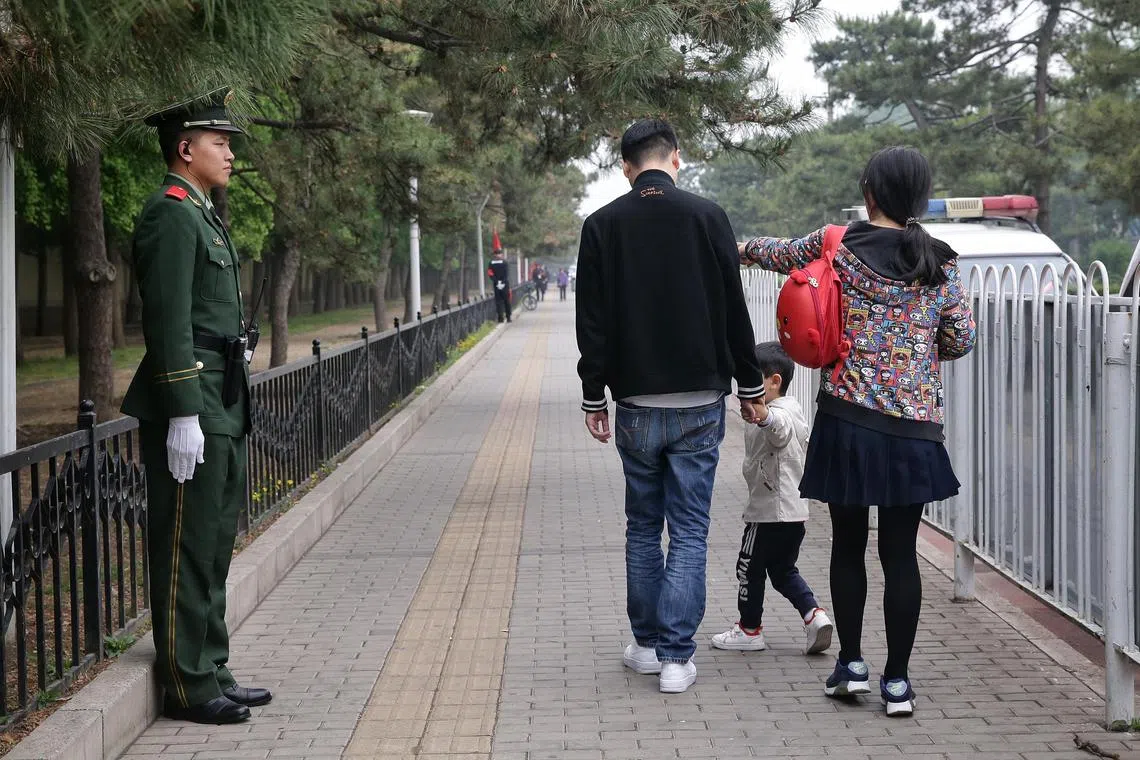 A family with a single child strolling past a military police outside Diaoyutai State Guesthouse in Beijing, China on 29 April 2019.