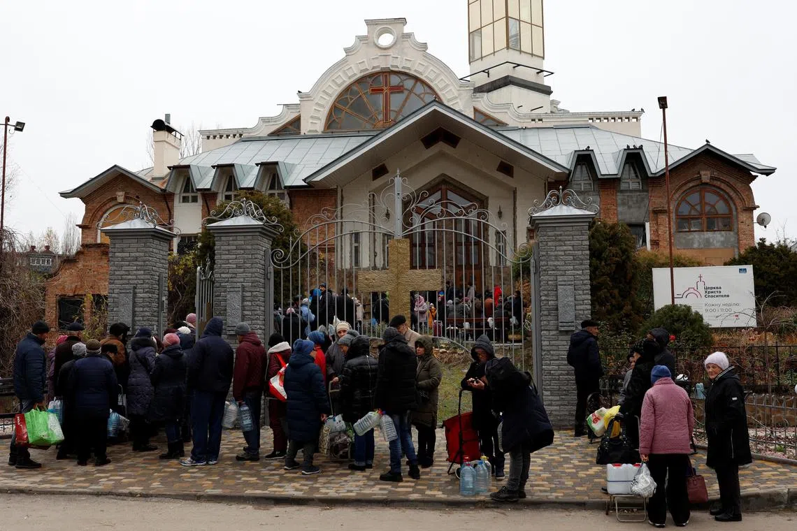 People wait in line to get food, water and aid outside the Church of Christ the Savior in Kherson, Ukraine, on Nov 22, 2022. 