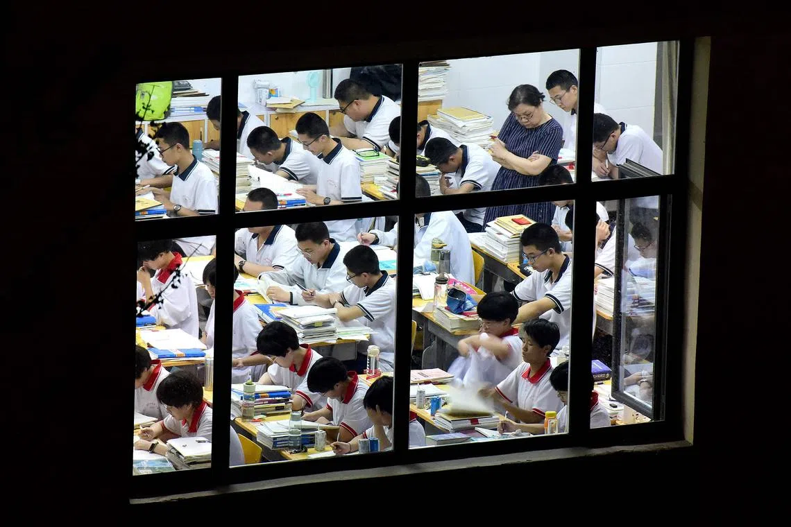 High school students go through exam papers, ahead of  China's national college entrance examination, known as the gaokao, on May 17, 2023. 
