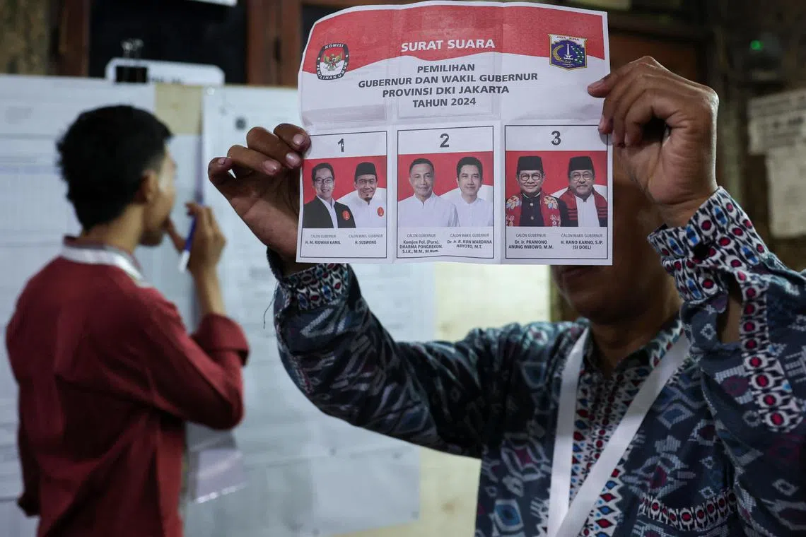 An electoral officer shows the ballot as they count votes at a polling station after regional elections in Jakarta, Indonesia.
