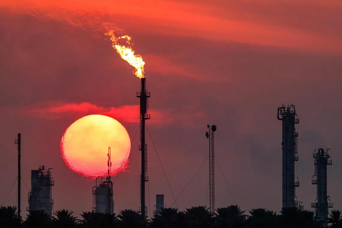 The sun sets behind burning gas flares at the Dora (Daura) Oil Refinery Complex in Baghdad on December 22, 2024. (Photo by AHMAD AL-RUBAYE / AFP)