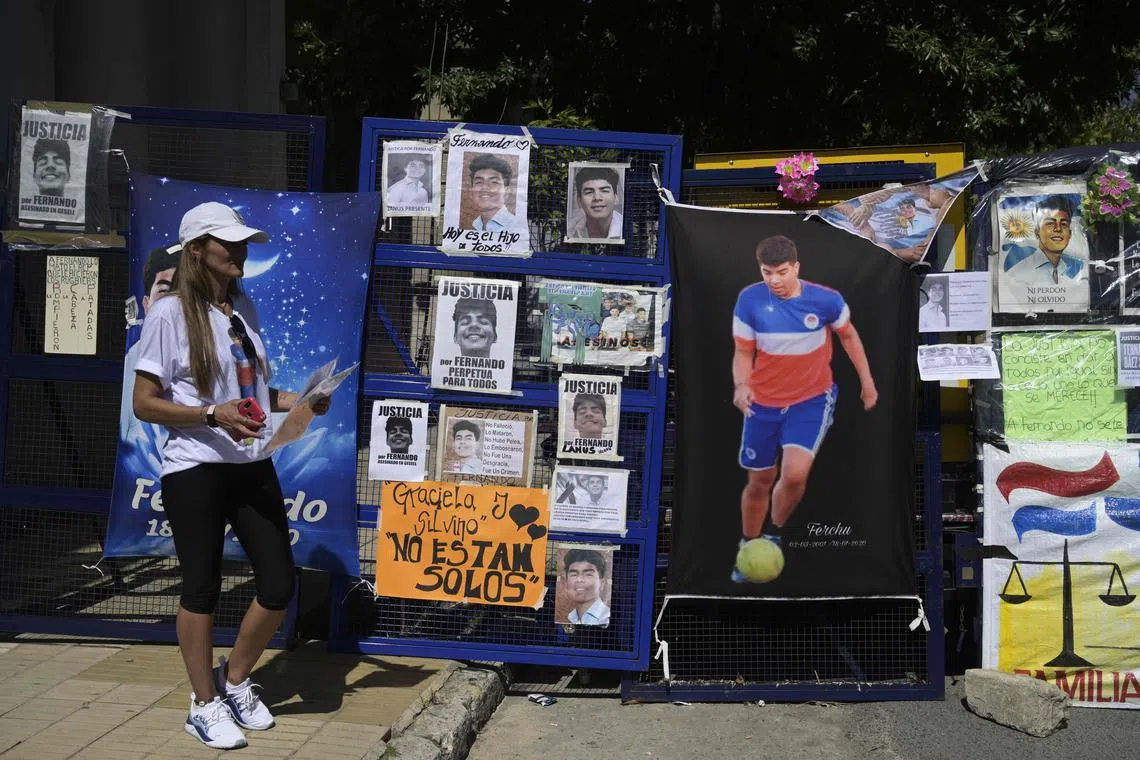 A woman stands next to a police fence covered with images in support of Fernando Baez Sosa - who was murdered by a group of amateur rugby players in 2020 - outside the court after the sentencing hearing in Dolores, Argentina.