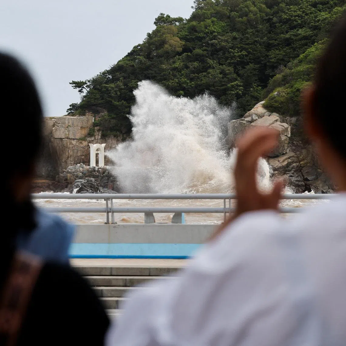 People watch waves crash against the shore as Typhoon Bavi approaches, in Wenzhou, Zhejiang province, China July 10, 2026. REUTERS/Go Nakamura