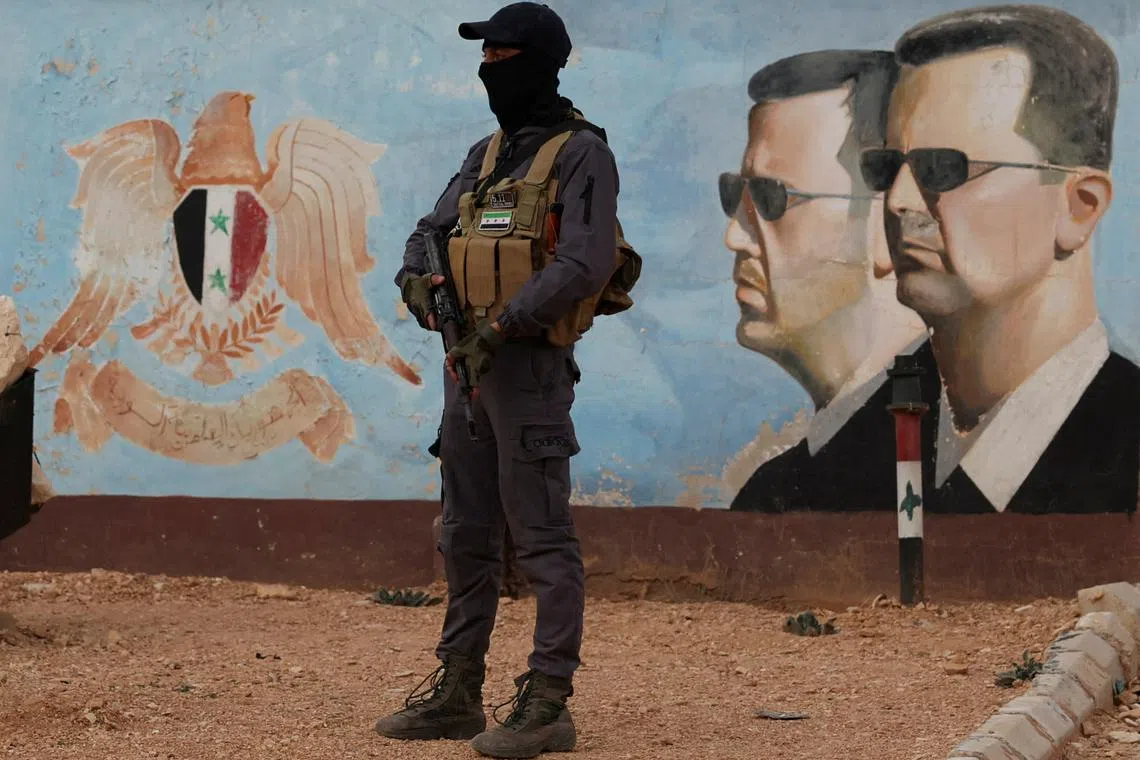 FILE PHOTO: A member of the former rebel group Hayat Tahrir al-Sham stands guard near an image of Syria's Bashar al-Assad at the fourth division headquarters in Damascus, Syria, January 23, 2025 REUTERS/Yamam Al Shaar/File Photo