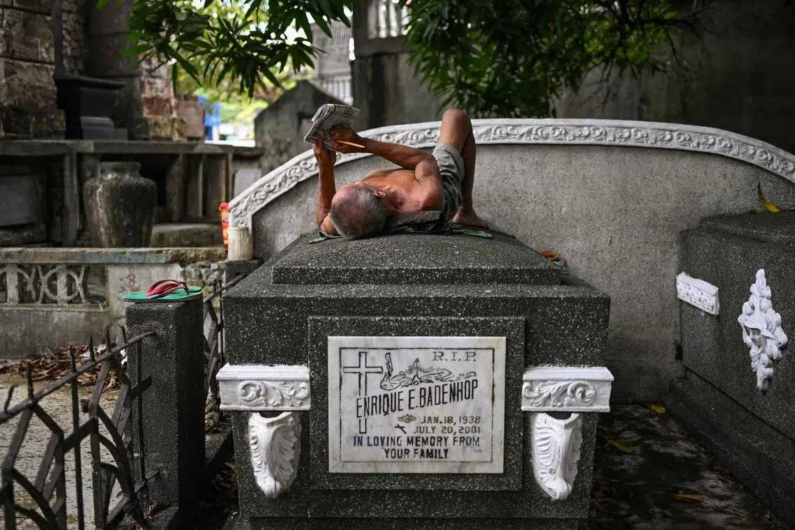 A man lies on top of a tomb at the 54ha Manila North Cemetery that is home to about 6,000 informal settlers and at least a million dead.
