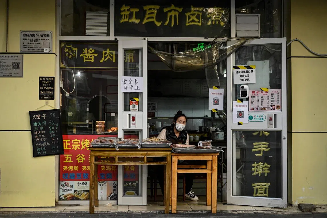 A woman waits for customers at a restaurant with dine-in services suspended in Beijing on Nov 19, 2022.