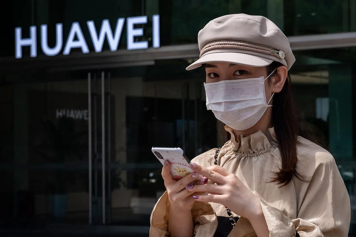 (FILES) In this file photo taken on May 25, 2020 a woman walks past a shop for Chinese telecoms giant Huawei in Beijing. - Revenue at Chinese telecom giant Huawei fell by 2.2 percent in the first three quarters of 2022, company data showed October 27, 2022, as Covid-19 and US sanctions dragged down sales. (Photo by NICOLAS ASFOURI / AFP)