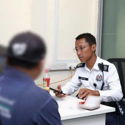 A Traffic Police officer speaking to two motorists about their outstanding fines.