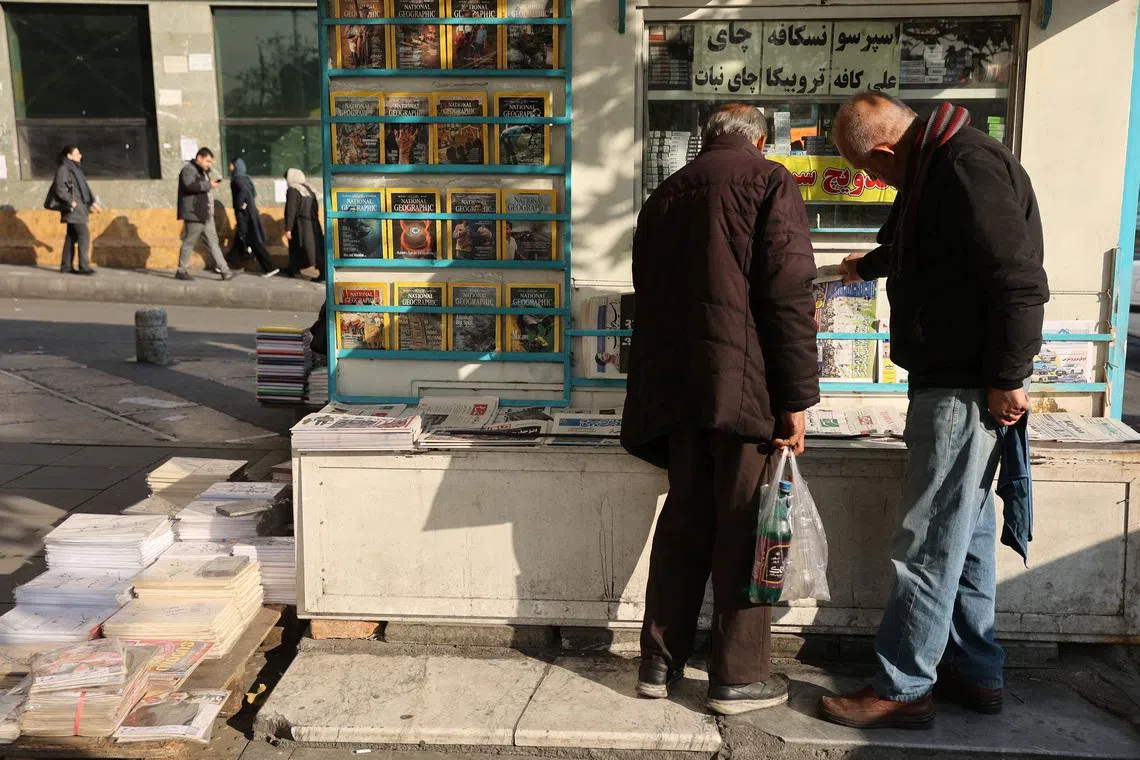 Iranian men read newspapers on a street, as protests erupt over the collapse of the currency's value, in Tehran, Iran, January 5, 2026. Majid Asgaripour/WANA (West Asia News Agency) via REUTERS