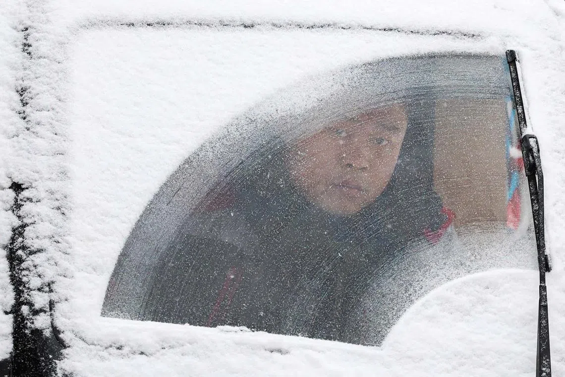 A delivery worker riding an electric vehicle amid snowfall in Beijing, China, Dec 14, 2023. 