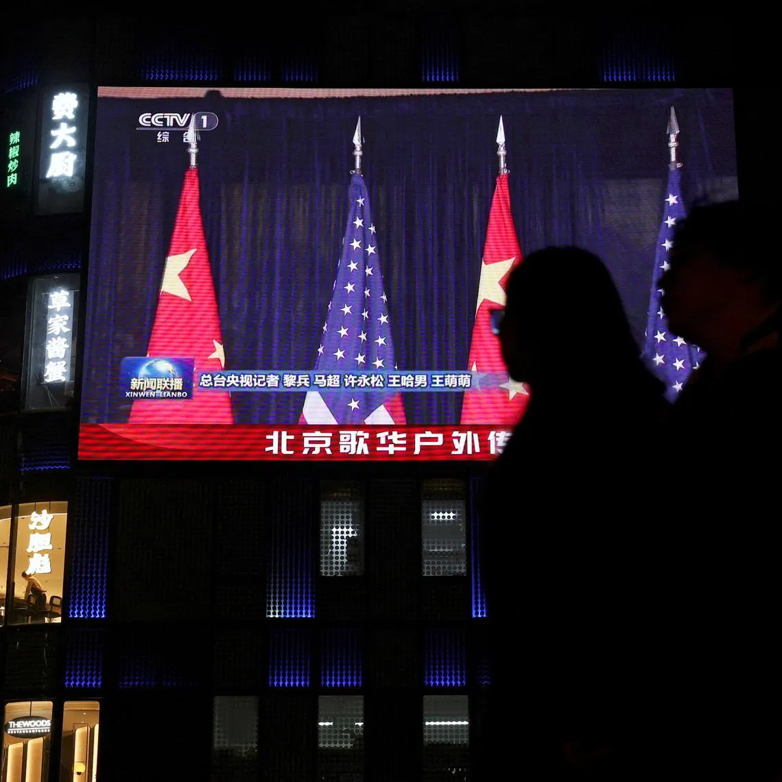 FILE PHOTO: A large screen shows news footage of Chinese and U.S. flags during the bilateral meeting between Chinese President Xi Jinping and U.S. President Donald Trump on the sidelines of the Asia-Pacific Economic Cooperation (APEC) summit in South Korea's Busan, outside a shopping mall in Beijing, China October 30, 2025. REUTERS/Florence Lo/File Photo