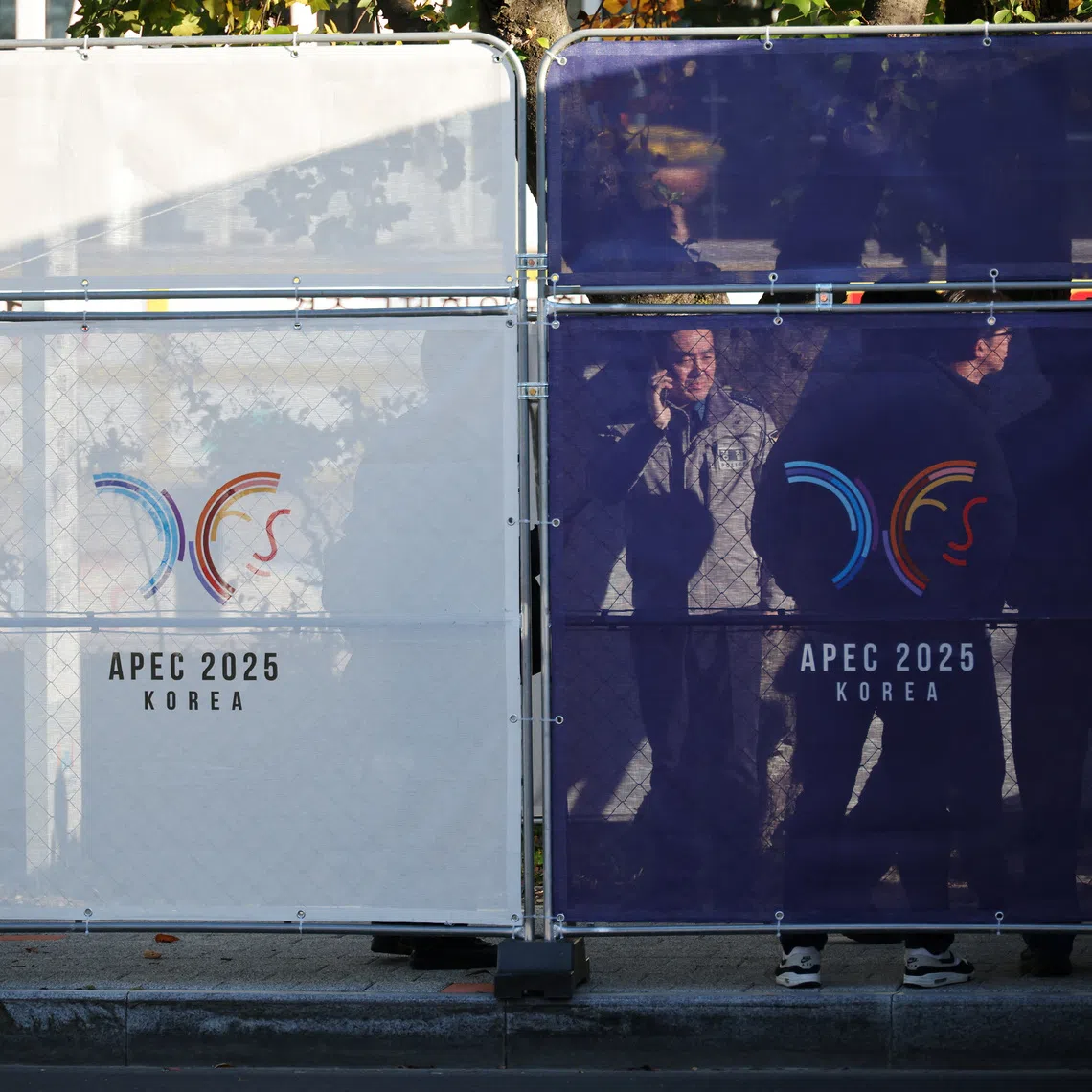 People stand behind fences bearing the logo of 2025 Asia-Pacific Economic Cooperation leaders' summit, at the venue for the summit in Gyeongju, South Korea, October 28, 2025.   REUTERS/Kim Hong-Ji