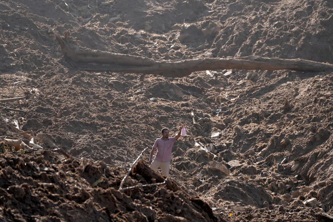 A man holds up a food packet as he moves through mud after landslides triggered by heavy rainfall following Cyclone Ditwah, in Mawathura in Kandy district, Sri Lanka, December 3, 2025. REUTERS/Thilina Kaluthotage