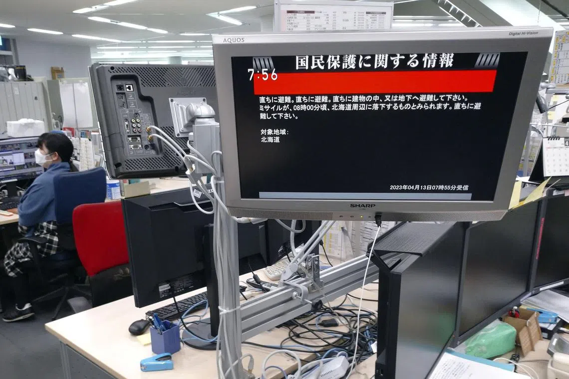 A TV screen displays a warning message after the Japanese government issued an alert, following a ballistic missile launch by North Korea, at an office in Tokyo, Japan, on April 13, 2023.