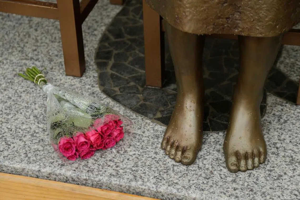 FILE PHOTO: A bouquet lays alongside a statue commemorating Korean \"comfort women\" at a Sydney church in Sydney, Australia December 15, 2016, a 1.5-metre statue imported from Korea which has been a flashpoint for tensions between Korean and Japanese communities in Sydney since it was unveiled in August. REUTERS/Jason Reed/File Photo
