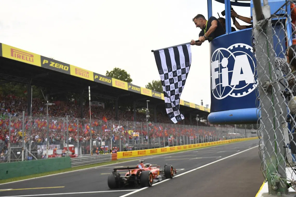 Formula One F1 - Italian Grand Prix - Autodromo Nazionale Monza, Monza, Italy - September 1, 2024 Ferrari's Charles Leclerc passes the chequered flag, waved by former footballer Alessandro Del Piero to win the Italian Grand Prix Massimo Pinca/Pool via REUTERS