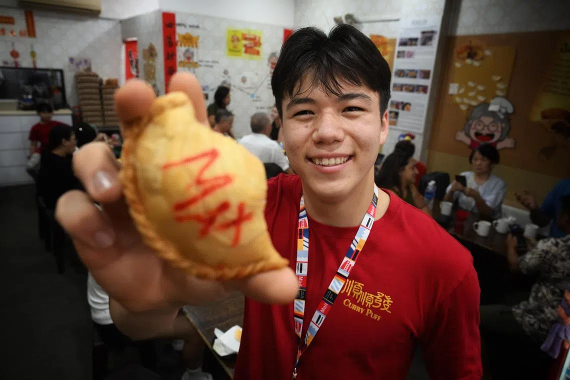 Max Maeder holds up a curry puff bearing his name during his one day stint working at the Soon Soon Huat curry puff shop in Katong.