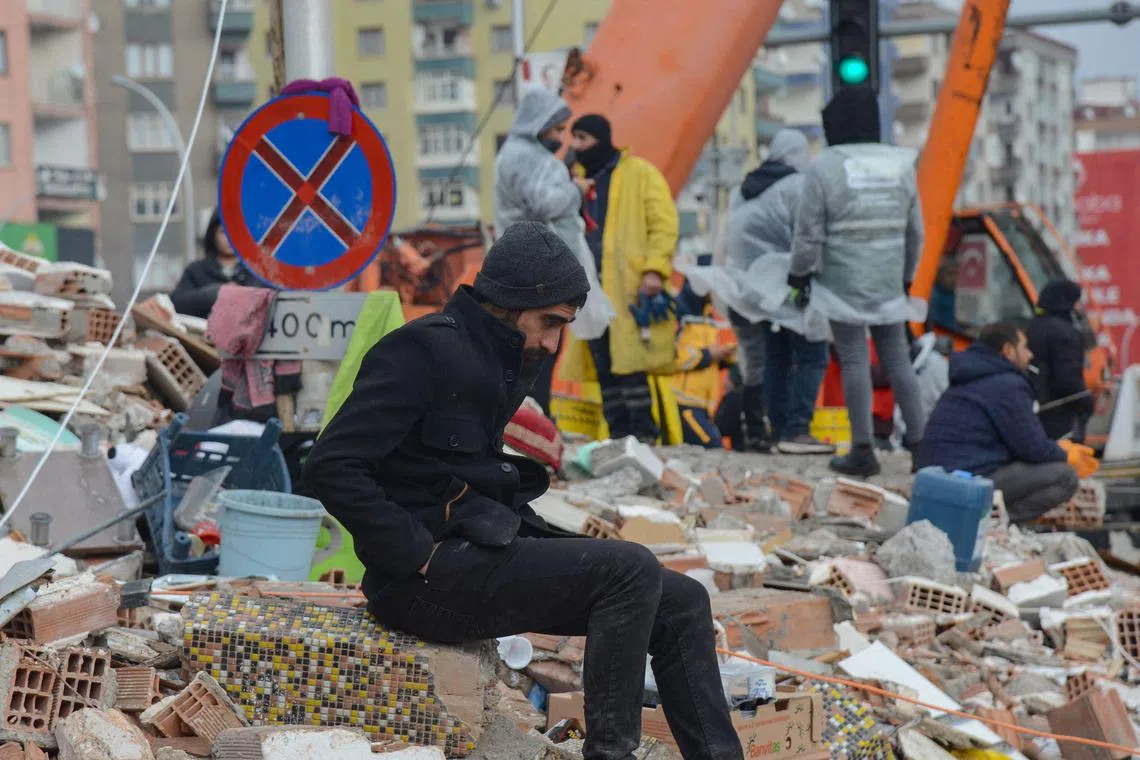 A man looks on as rescuers search for victims and survivors in the rubble of buildings, in Diyarbakir, on Feb 7, 2023.