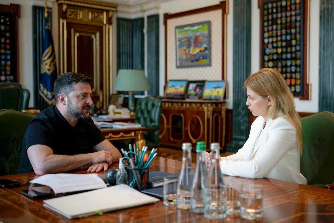 A man and a woman seated at a large table in a formal room.