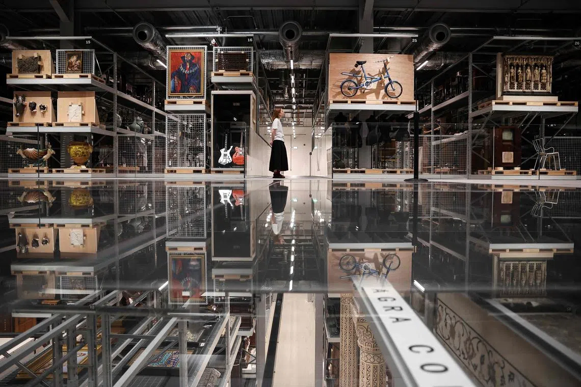 A visitor looks at the artefacts exhibited in the newly opened museum V&A East Storehouse, in East London, on June 12, 2025. London's V&A has launched a revolutionary new exhibition space, where visitors can choose from some 250,000 objects, order something they want to spend time looking at, and have it delivered to a room for a private viewing. One fifth of the museum's total collection is now available to be viewed and enjoyed in the four-storey building on the former site of the 2012 London Olympic Games. (Photo by HENRY NICHOLLS / AFP)