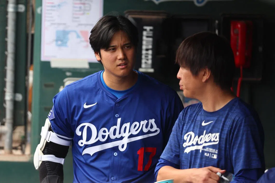 Mar 12, 2024; Phoenix, Arizona, USA; Los Angeles Dodgers designated hitter Shohei Ohtani talks with translator Ippei Mizuhara in the dugout against the San Francisco Giants during a spring training baseball game at Camelback Ranch-Glendale. Mandatory Credit: Mark J. Rebilas-USA TODAY Sports/File Photo