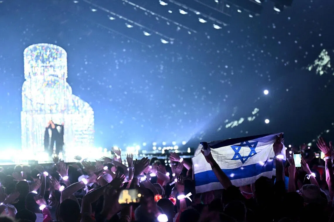 A member of the audience waving Israel's national flag as Israeli singer Yuval Raphael performs during the Eurovision Song Contest in Basel, Switzerland, in May 2025.