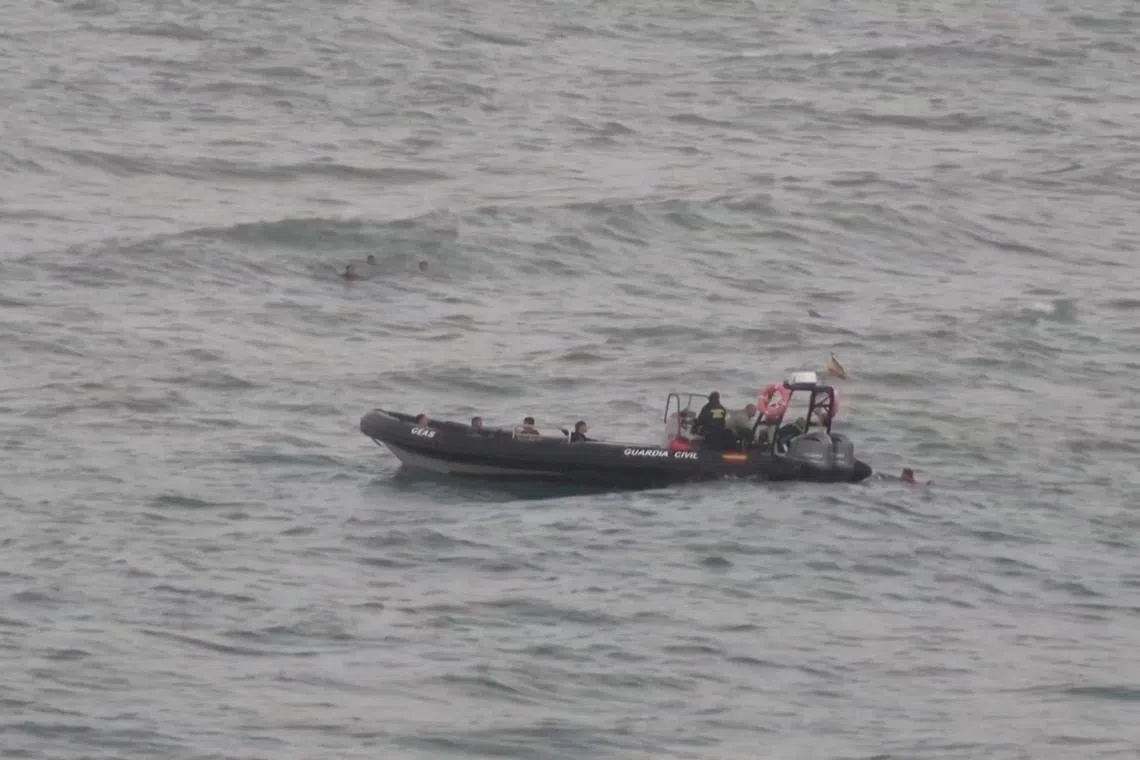 A view shows migrants reaching a police boat, while other group of migrants swim in the background, as at least 54 children and about 30 adults swam from Morocco to Spain's North African enclave of Ceuta, in Ceuta, Spain July 25, 2025, in this screengrab obtained from a video. FARO TV/Handout via REUTERS