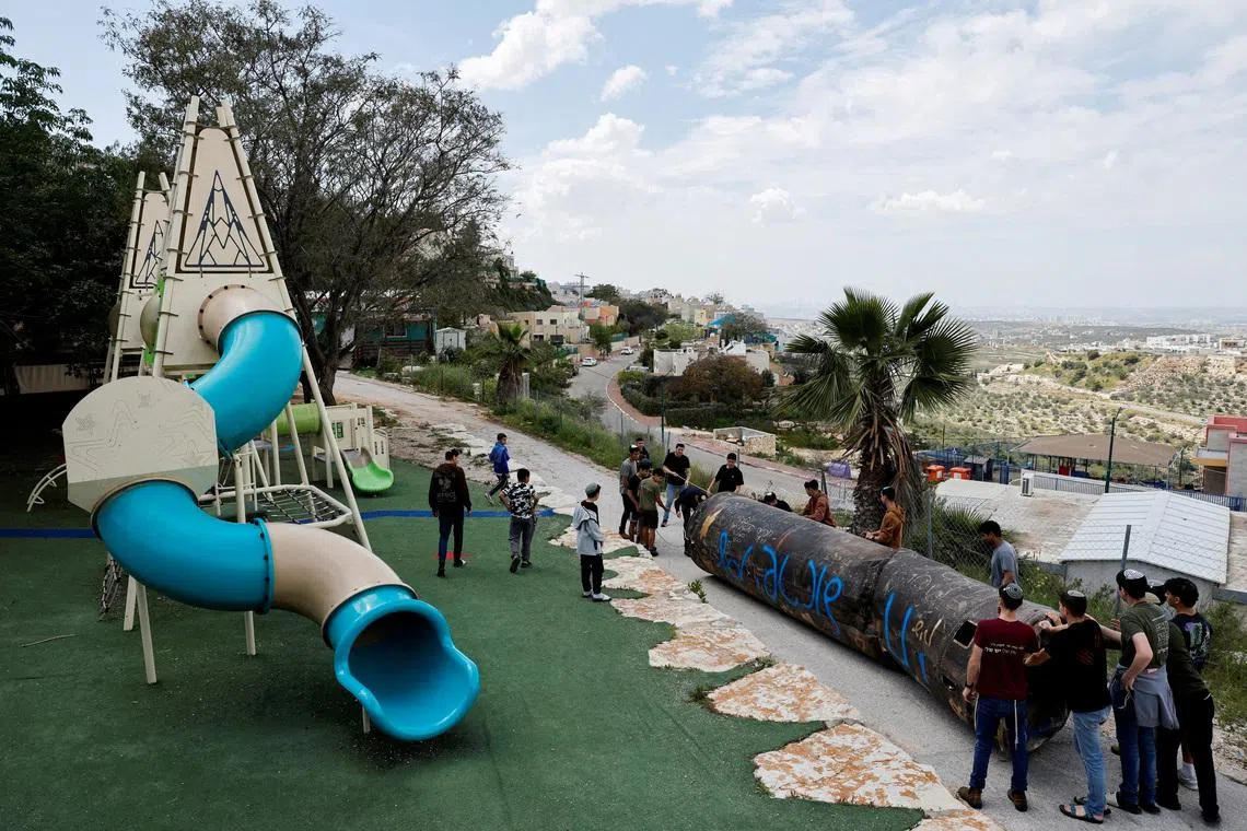 FILE PHOTO: Teenagers drag a part of a missile that landed in the playground of an elementary school last night, amid the U.S.-Israel conflict with Iran, in the Israeli settlement Peduel of the Israel-occupied West Bank, March 23, 2026. REUTERS/Amir Cohen/File Photo