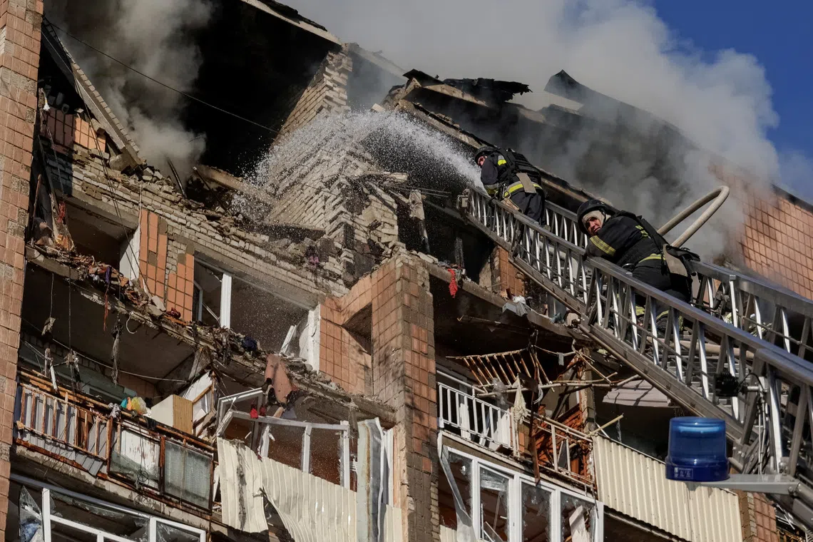 Firefighters work at the site of an apartment building damaged during a Russian drone strike in Kharkiv, Ukraine, on Oct 12.