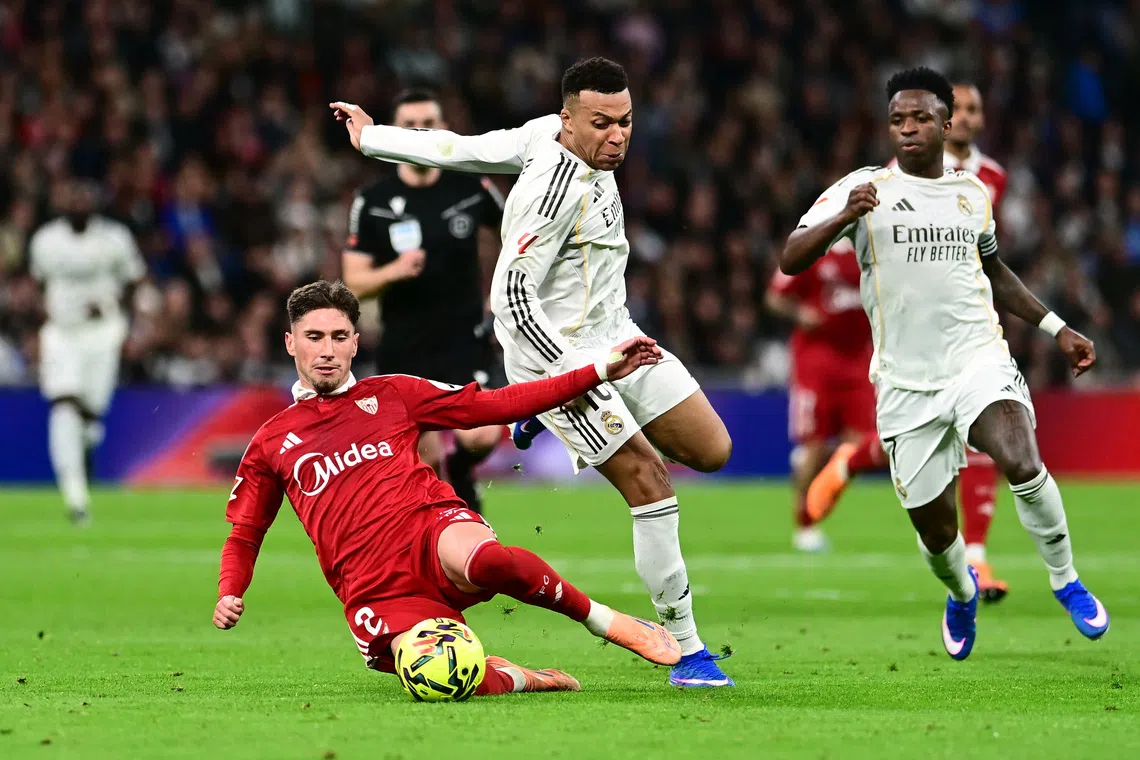Soccer Football - LaLiga - Real Madrid v Sevilla - Santiago Bernabeu, Madrid, Spain - December 20, 2025 Sevilla's Jose Angel Carmona in action with Real Madrid's Kylian Mbappe and Vinicius Junior REUTERS/Juan Barbosa