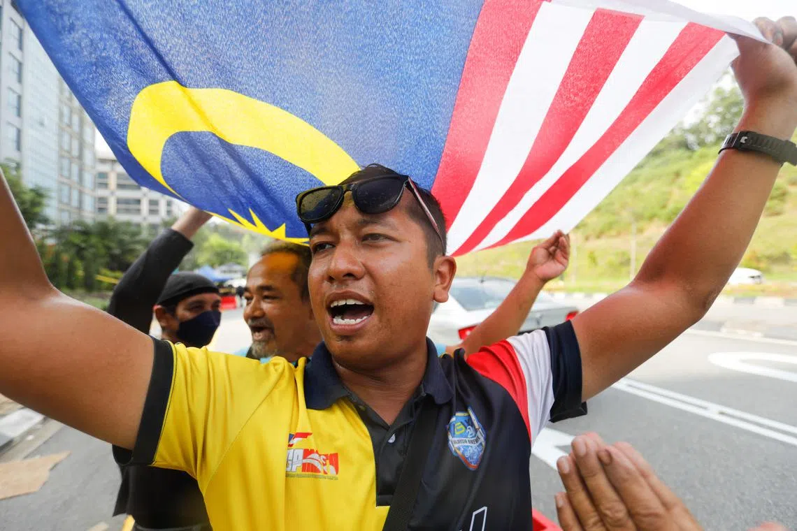 Supporters of Malaysia's new Prime Minister Anwar Ibrahim hold the national flag as they celebrate outside the Istana Negara (National Palace) in Kuala Lumpur. With no single bloc holding a sufficient majority, Datuk Seri Anwar is seen stewarding a “unity government”.