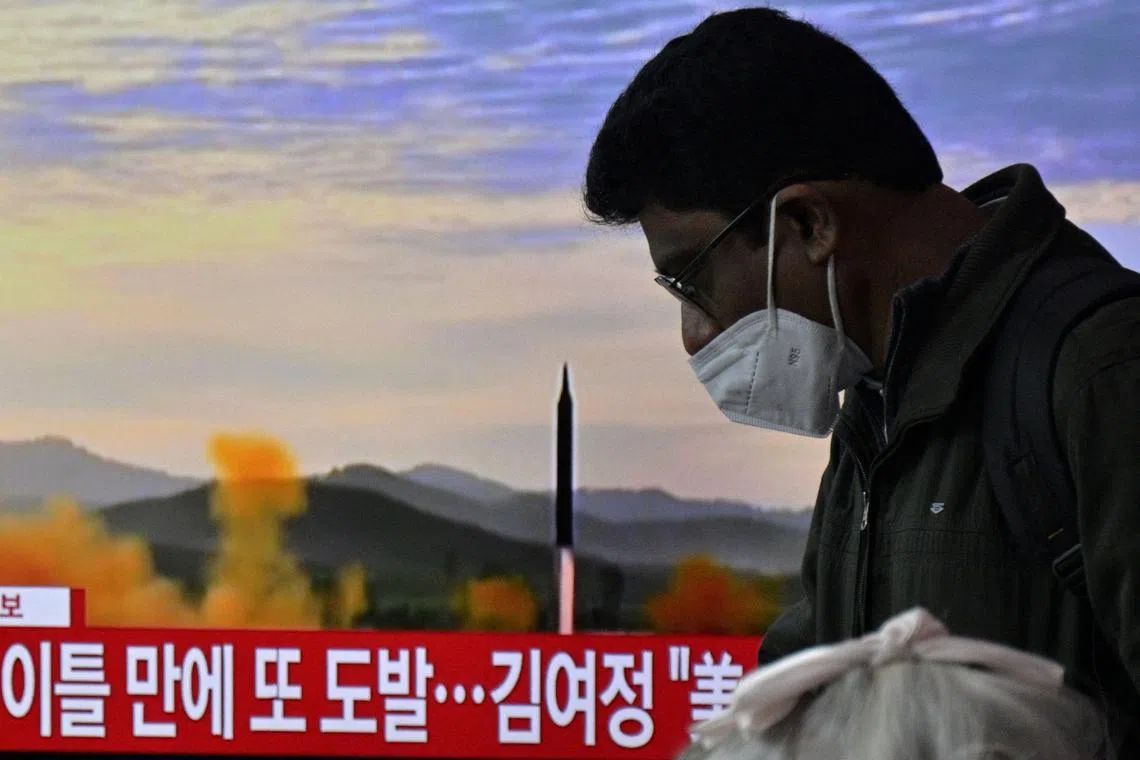 A man walks past a television showing a news broadcast with file footage of a North Korean missile test, at a railway station in Seoul on February 20, 2023. (Photo by Anthony WALLACE / AFP)