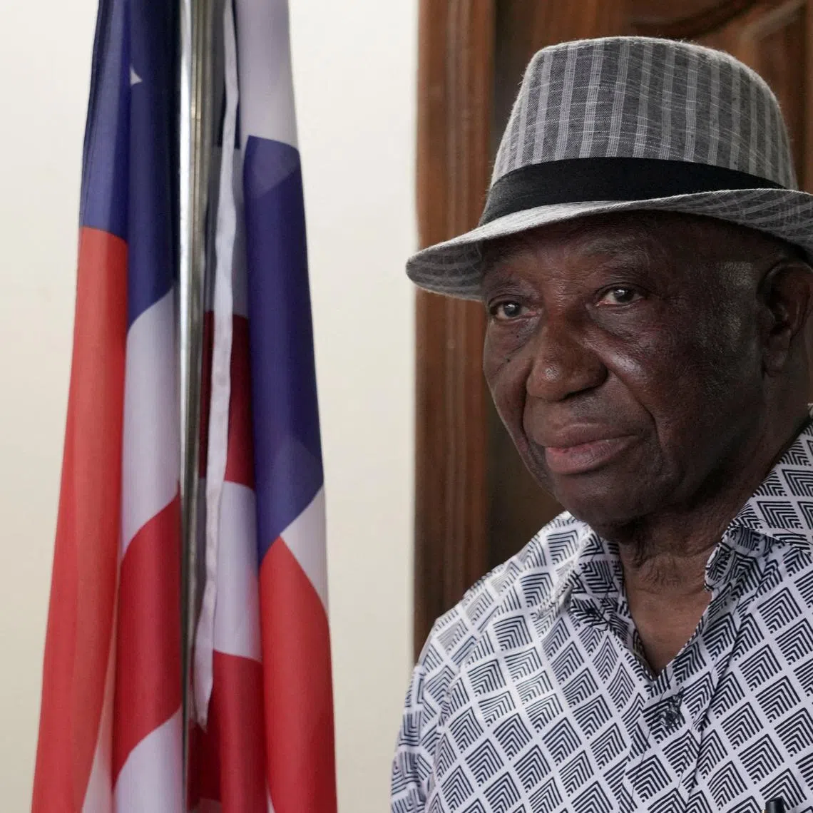 FILE PHOTO: Opposition Unity Party and Liberia president-elect Joseph Boakai looks on next to a Liberian flag, at his home in Monrovia, November 19, 2023. REUTERS/Carielle Doe/File Photo
