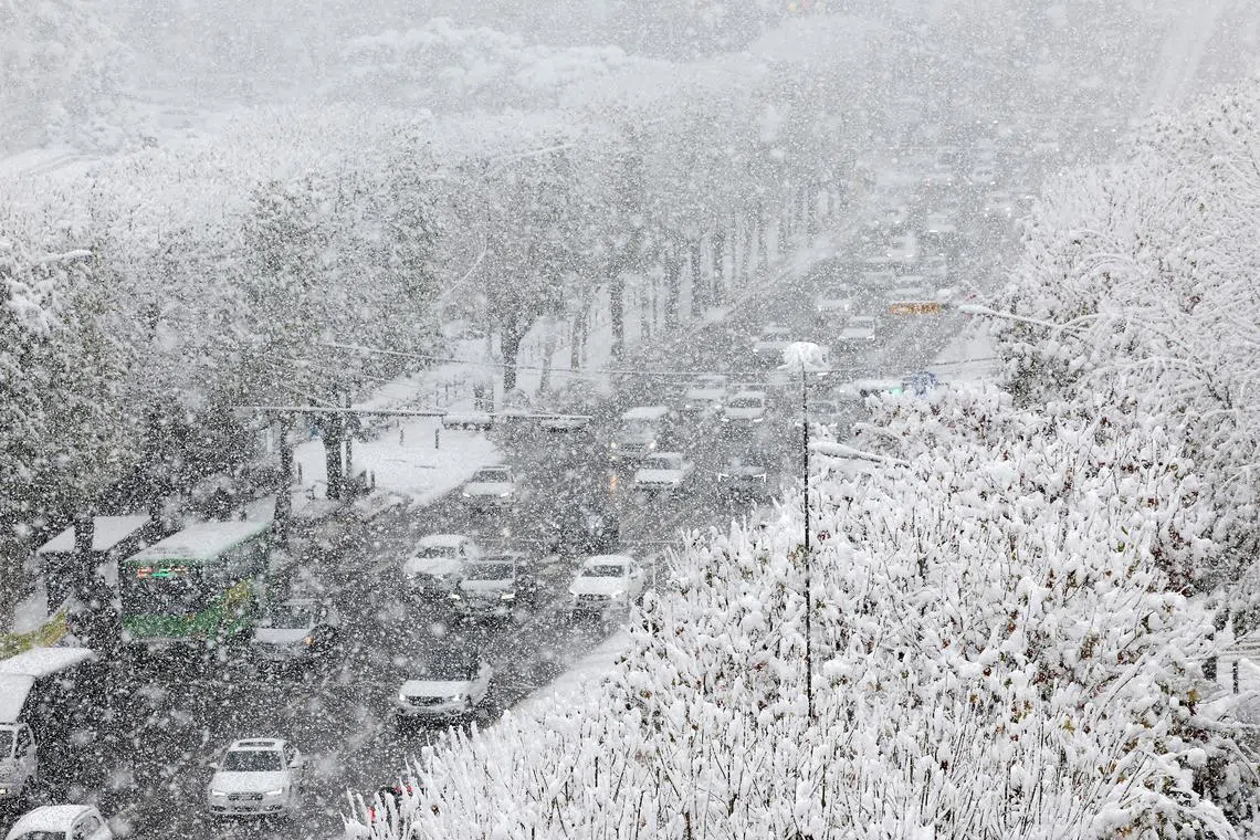 Cars moving slowly on a snow-covered road in Seoul on Nov 27, 2024, amid a heavy snowfall.