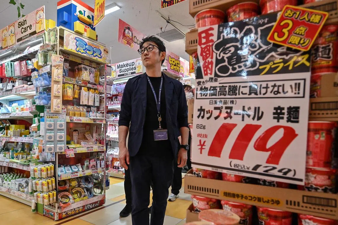 This photo taken on April 21, 2025 shows Motoki Hata, inbound support department manager, walking past cup noodles (R) for sale during an interview with AFP at a branch of Japanese discount retailer Don Quijote, also known overseas as Don Don Donki, in the Shibuya district of central Tokyo. In the narrow, crowded aisles of a department store in Tokyo's Shibuya district, hundreds of tourists rush to fill their baskets with snacks, gadgets, and souvenirs of all kinds, fuelling sales at Don Quijote, the king of Japanese discount stores. (Photo by Richard A. Brooks / AFP) / To go with AFP story Japan-tourism-economy-retail,FOCUS by Caroline Gardin and Atish Patel