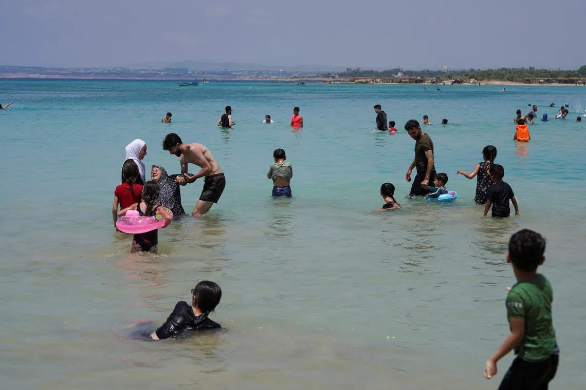People swim at a public beach in Latakia, Syria June 12, 2025. REUTERS/Karam Al-Masri