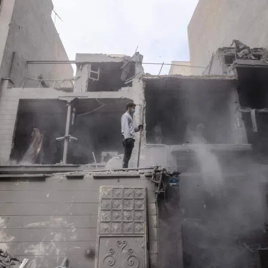 An Iranian man stands on a wall of damaged homes following a military strike on the Iranian capital Tehran on March 15, 2026. Iran's Foreign Minister said in an interview published on March 15, that the war pitting his country against the United States and Israel will only end when Tehran can be certain it will not be restarted. On February 28, Israel and the United States launched strikes on Iran, killing its supreme leader Ayatollah and triggering a war that spread across the Middle East. (Photo by Atta KENARE / AFP) /