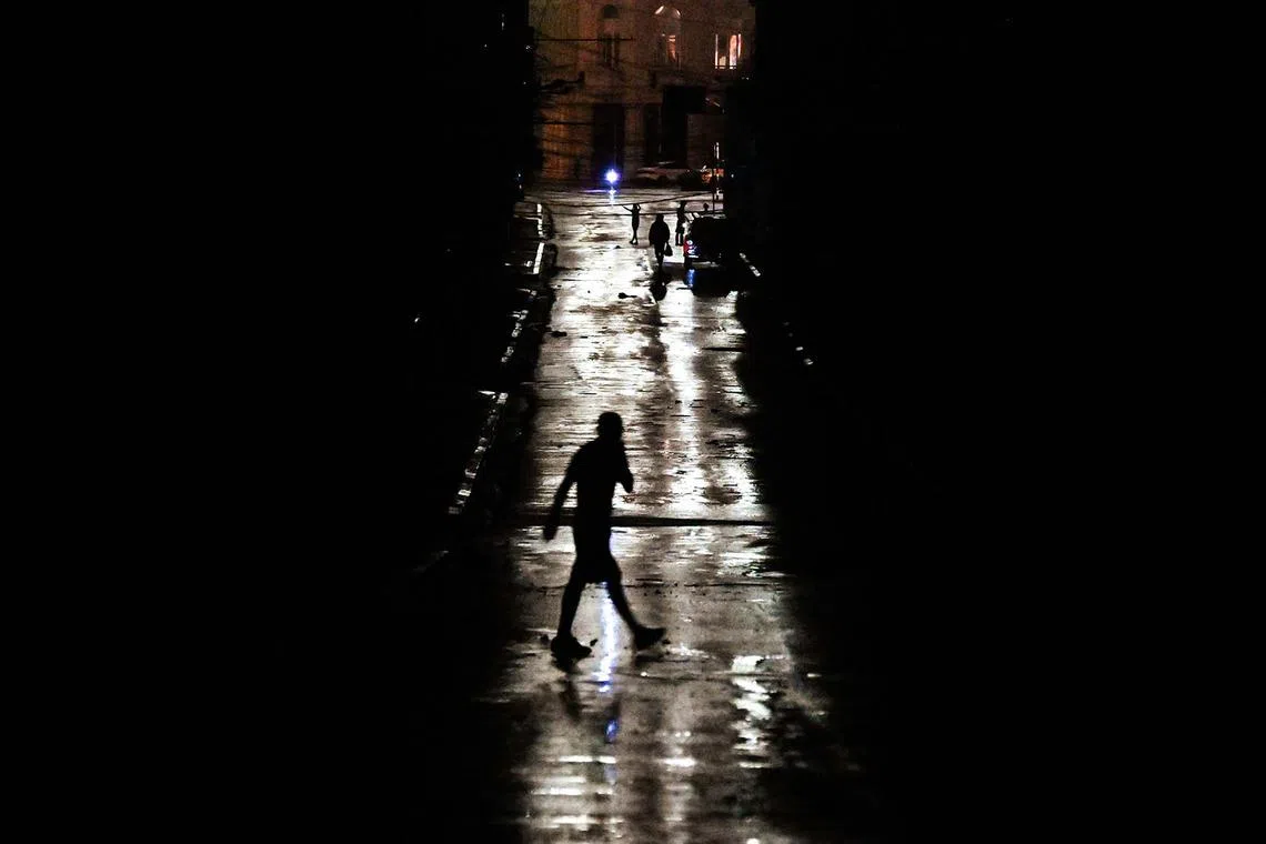 People walking on a darkened street due to a blackout after hurricane Rafael passes by in Havana, on Nov 6, 2024. 