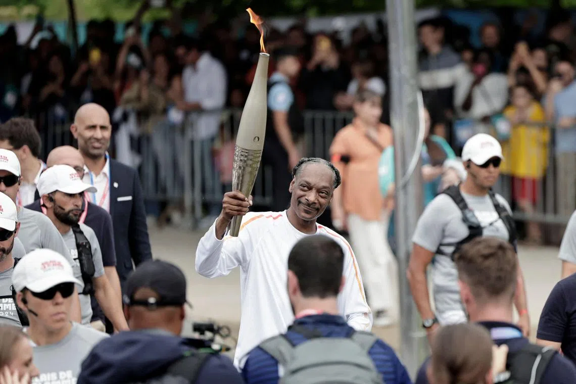 TOPSHOT - US rapper Snoop Dogg holds the torch as part of the 2024 Paris Olympic Games Torch Relay, on the day of the opening ceremony, in Saint-Denis, outside Paris, on July 26, 2024. (Photo by STEPHANE DE SAKUTIN / AFP)
