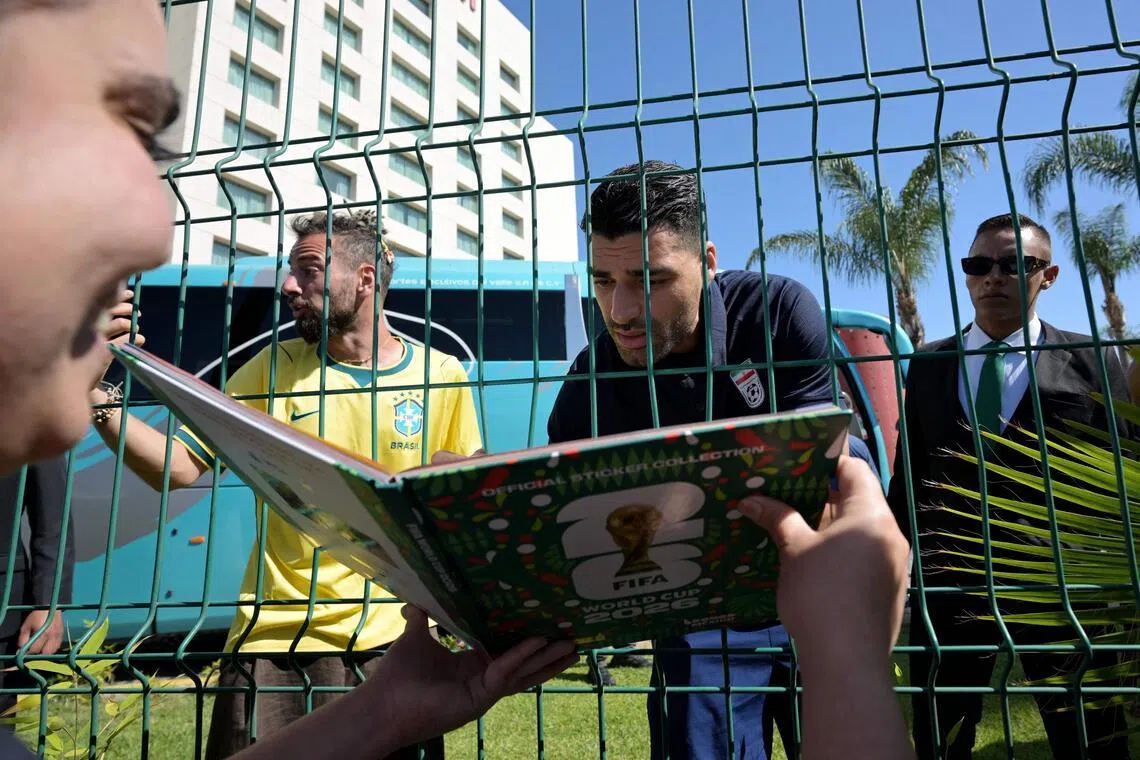 Iran's forward Mehdi Taremi signs autographs for a fan outside the Marriott Hotel in Tijuana, Mexico.